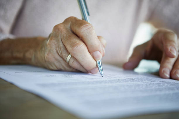 Personne âgée en train de signer un document sur les droits de succession