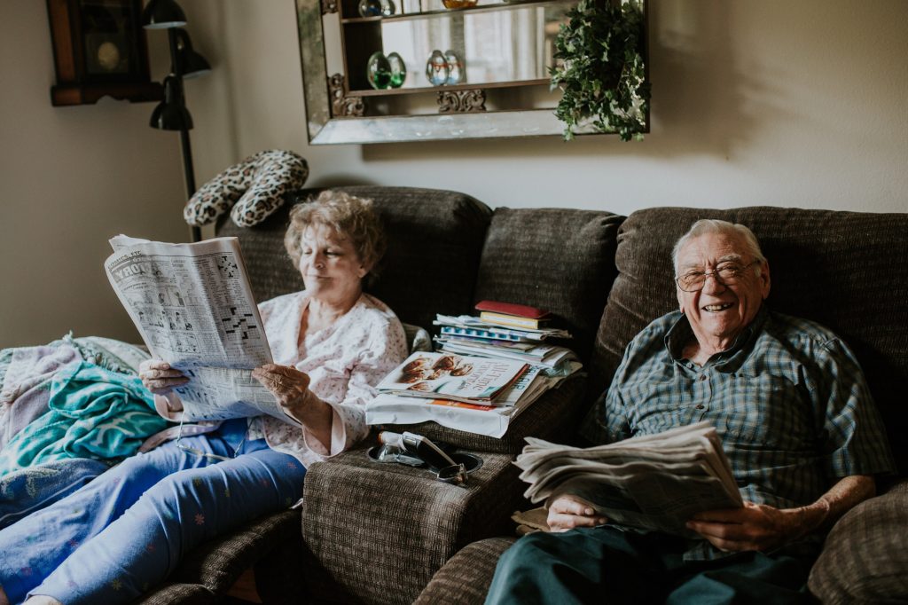 couple de seniors assis dans un canapé en train de lire