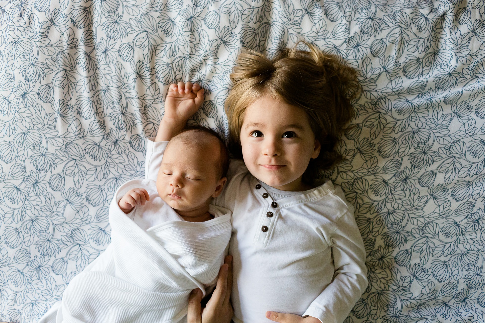 Un bébé et sa soeur allongés sur un lit